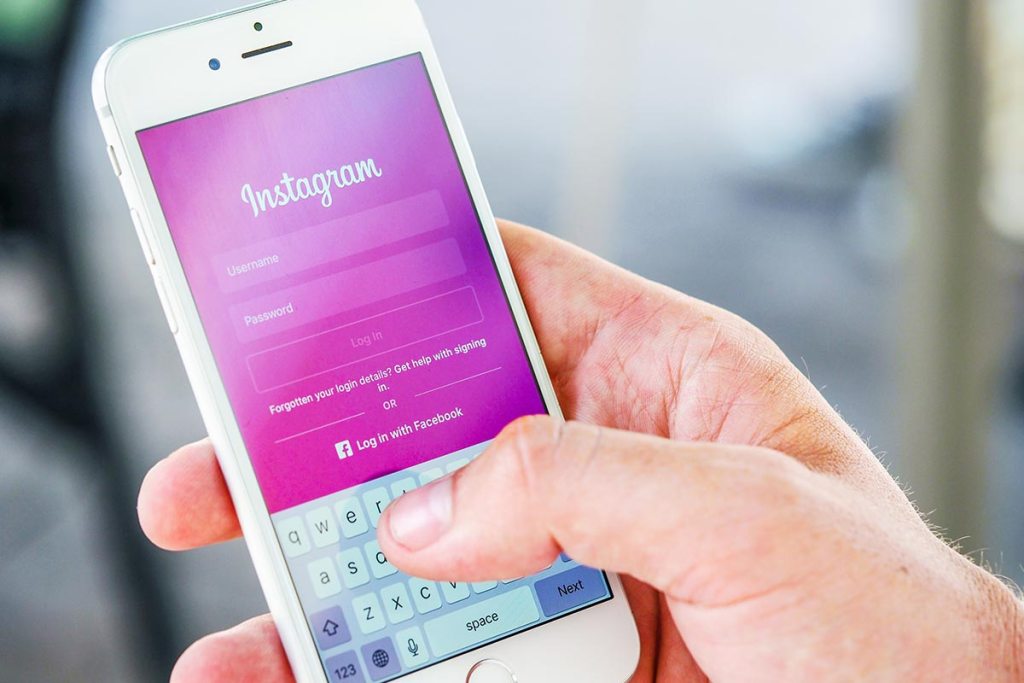 Mão a segurar no smartphone com o login de instagram|