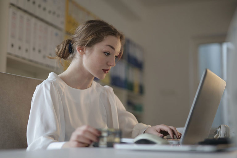Mulher com camisa branca usando laptop no escritório