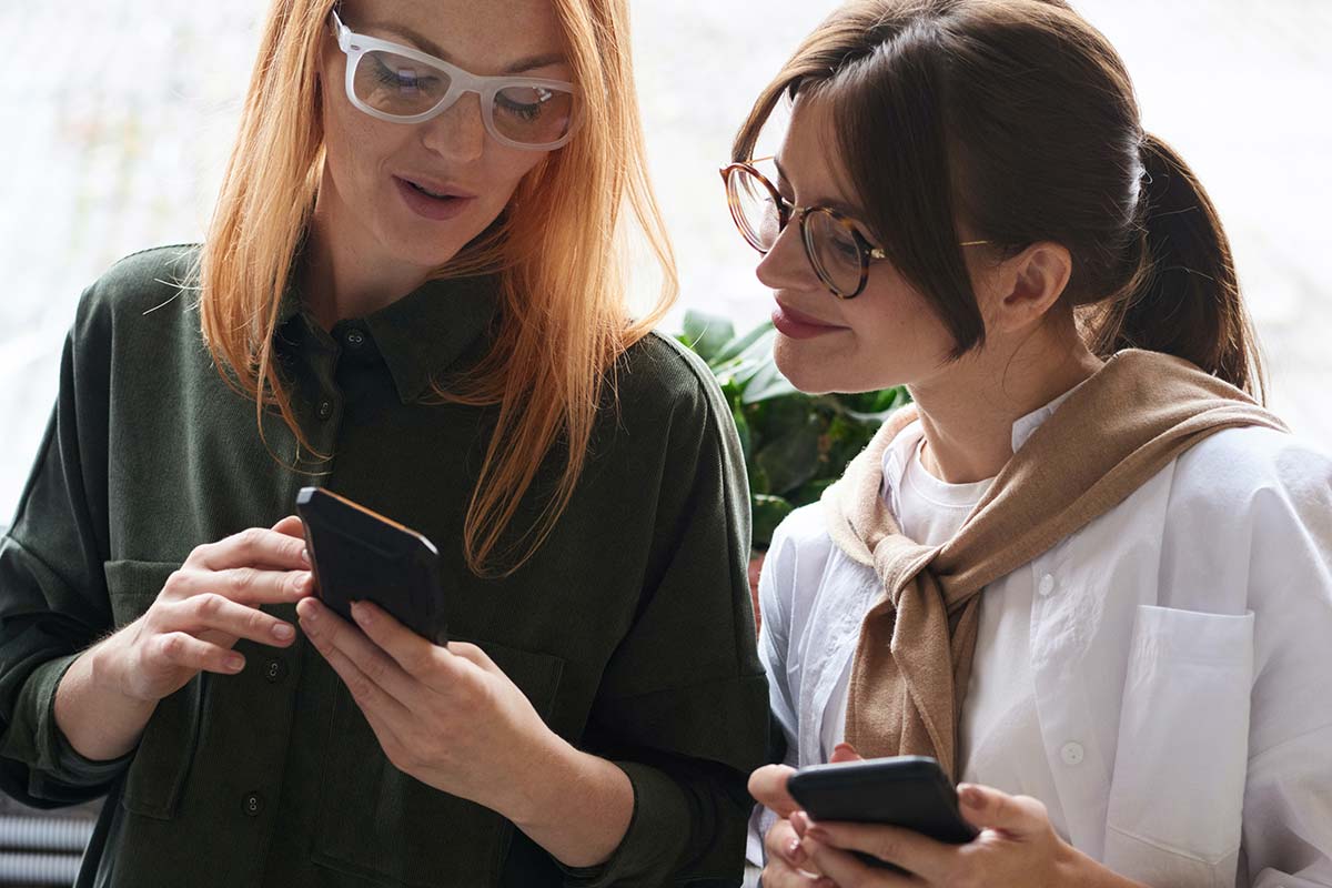 Mulheres no escritório a olhar ao telemóvel